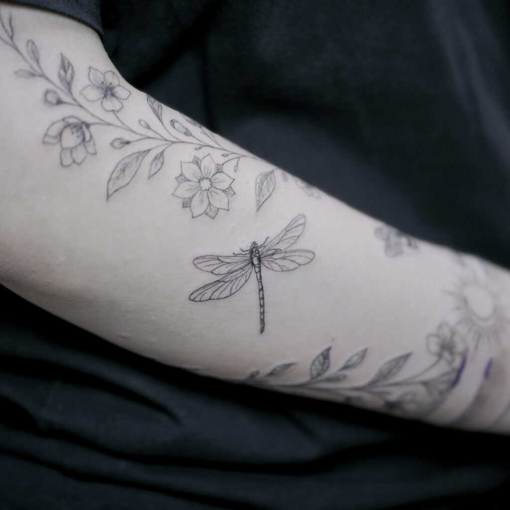 Fineline Tattoo am Unterarm mit floralen Elementen und Libelle, gestochen im LIghthouse Tattoo Studio in Straubing